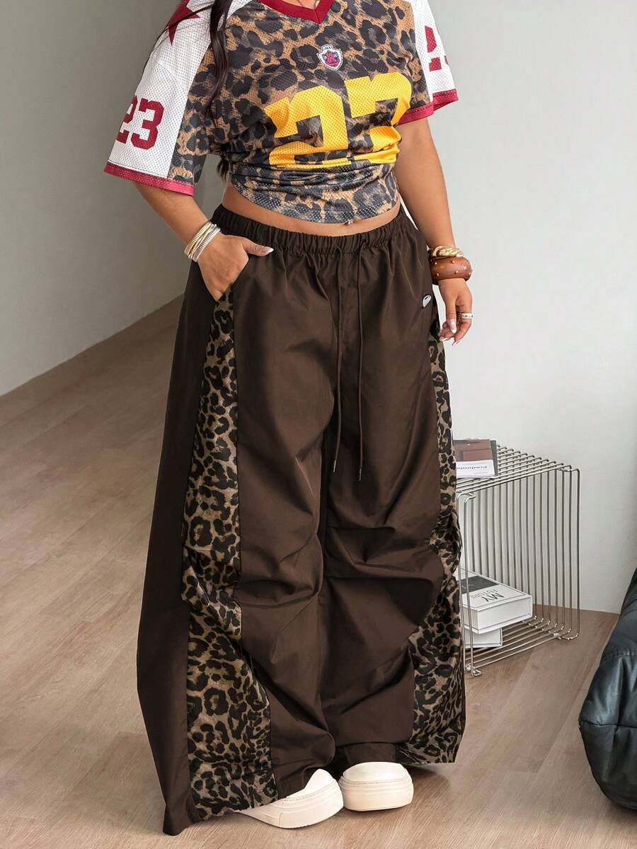 Women's high waist wide leg pants in black featuring leopard print patchwork details and an elastic drawstring waistband.