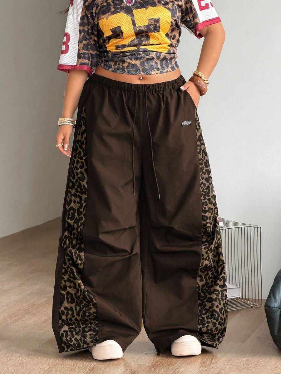 Women's high waist wide leg pants in black featuring leopard print patchwork details and an elastic drawstring waistband.