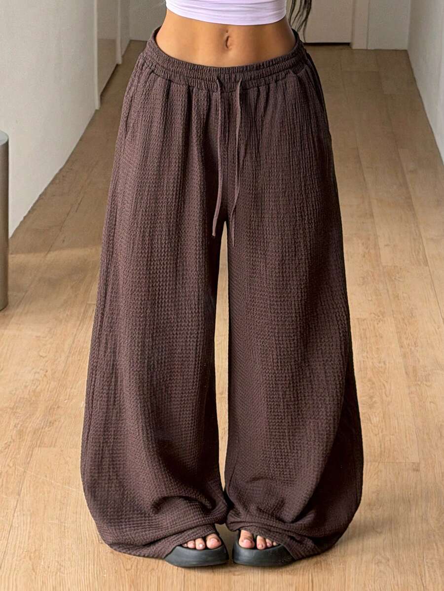 Women's loose straight leg cotton pants featuring a high waist with an adjustable drawstring knot and functional side pockets.