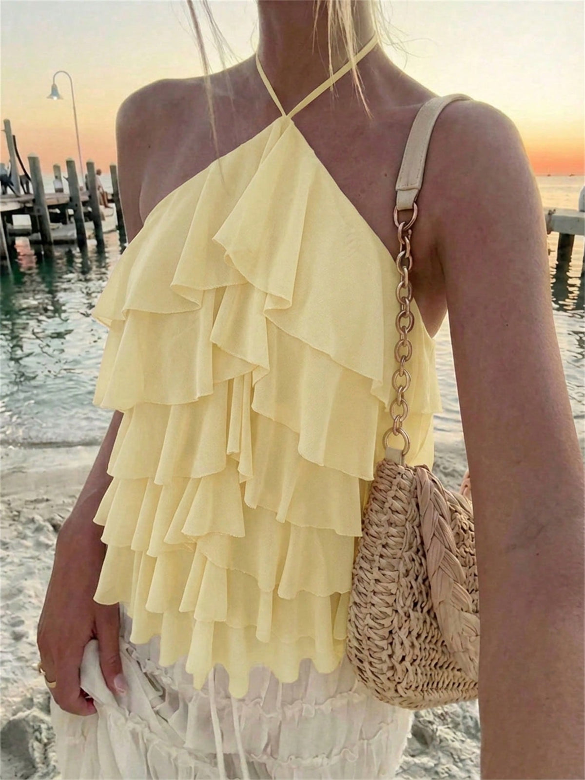 Women's sleeveless halter neck top featuring tiered ruffle layers, a backless cut, and an asymmetrical hem.