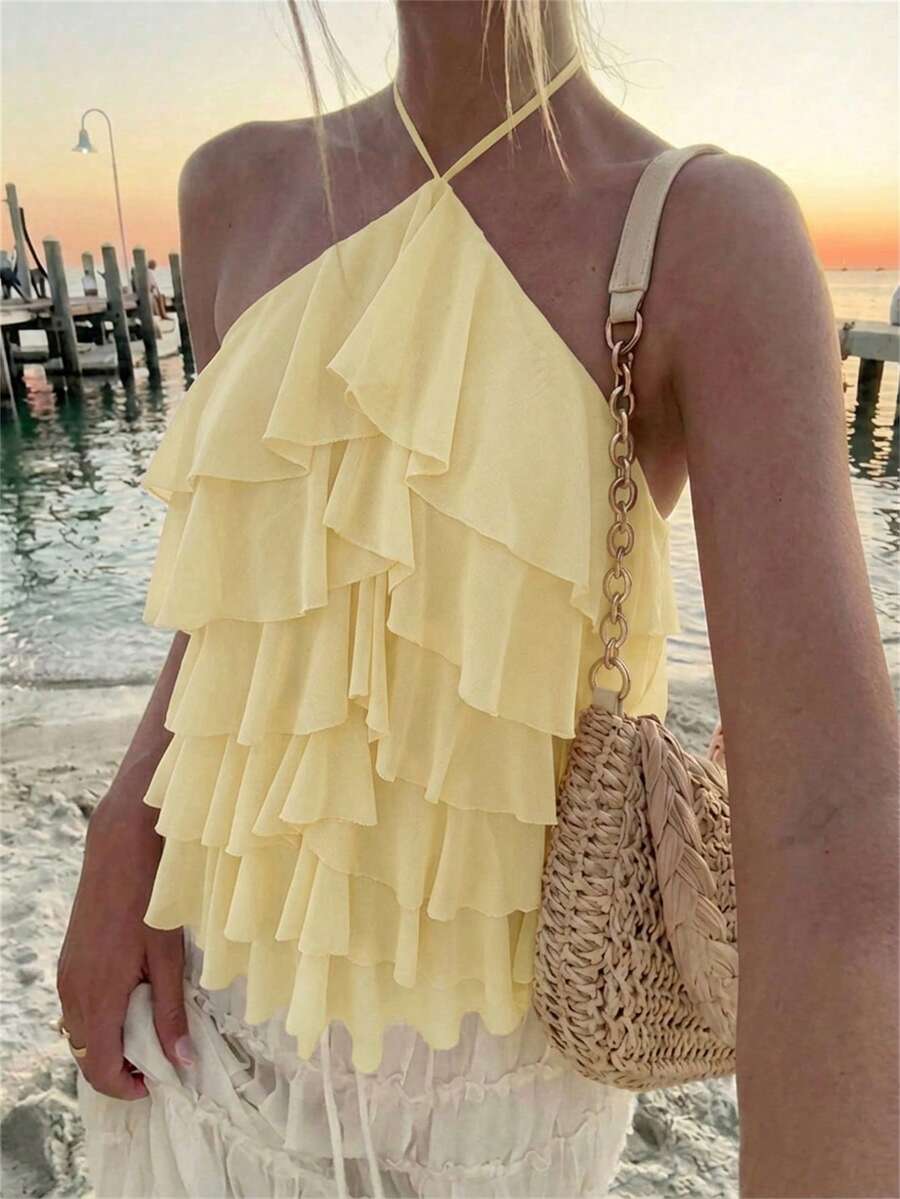 Women's sleeveless halter neck top featuring tiered ruffle layers, a backless cut, and an asymmetrical hem.