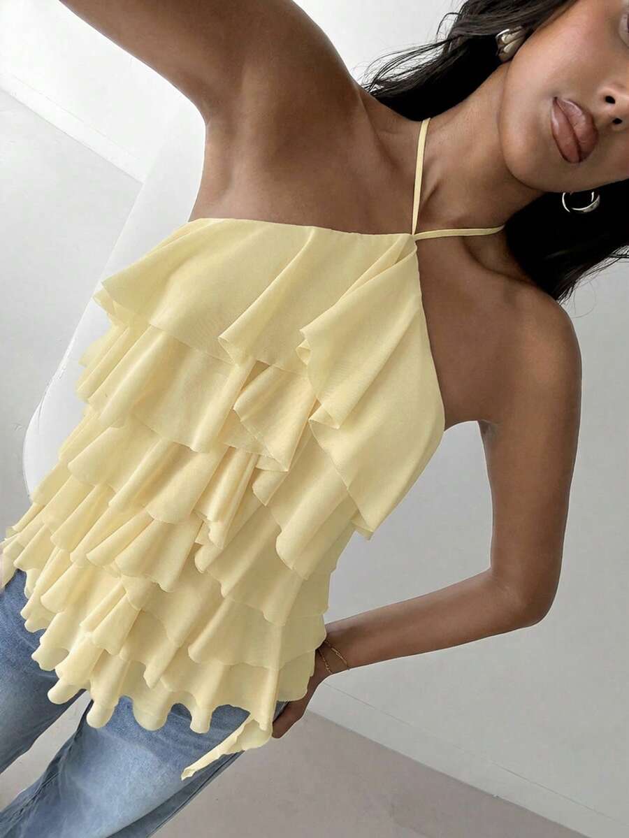 Women's sleeveless halter neck top featuring tiered ruffle layers, a backless cut, and an asymmetrical hem.