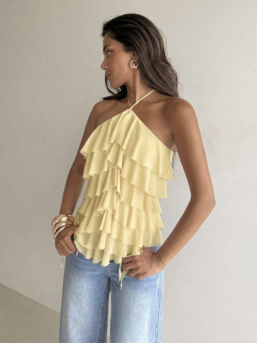 Women's sleeveless halter neck top featuring tiered ruffle layers, a backless cut, and an asymmetrical hem.