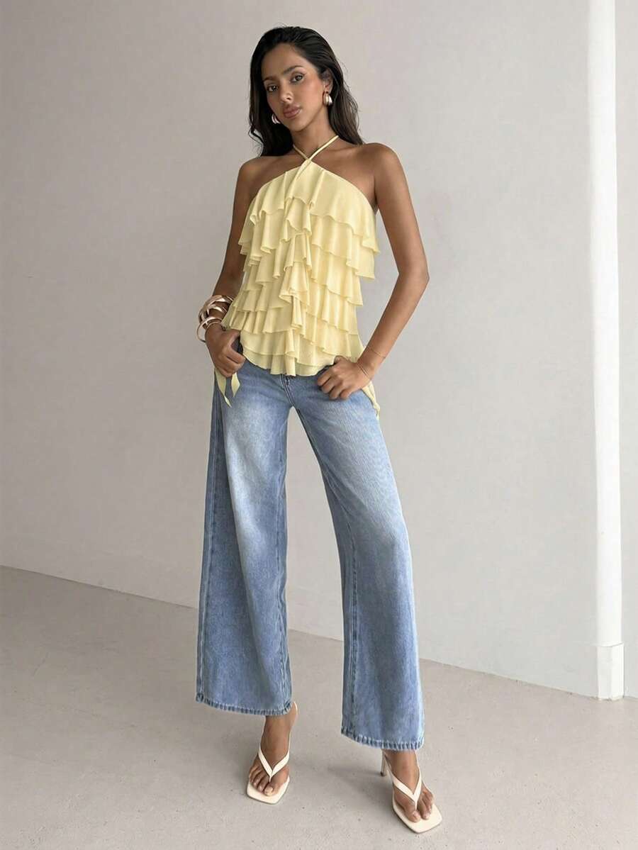 Women's sleeveless halter neck top featuring tiered ruffle layers, a backless cut, and an asymmetrical hem.