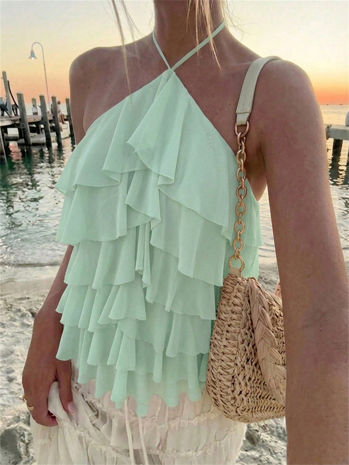 Women's sleeveless halter neck top featuring tiered ruffle layers, a backless cut, and an asymmetrical hem.