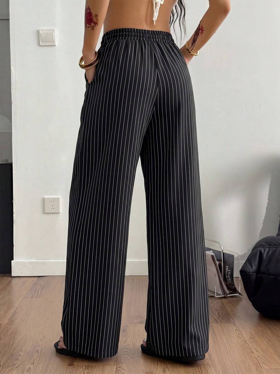 Women's black and white striped wide leg pants featuring an adjustable drawstring waist and side pockets.