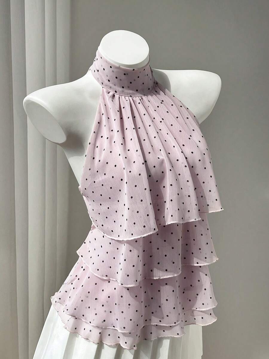 Women's white sleeveless halter neck top featuring pleated fabric, backless tie strap design, and a flared layered ruffle hem.