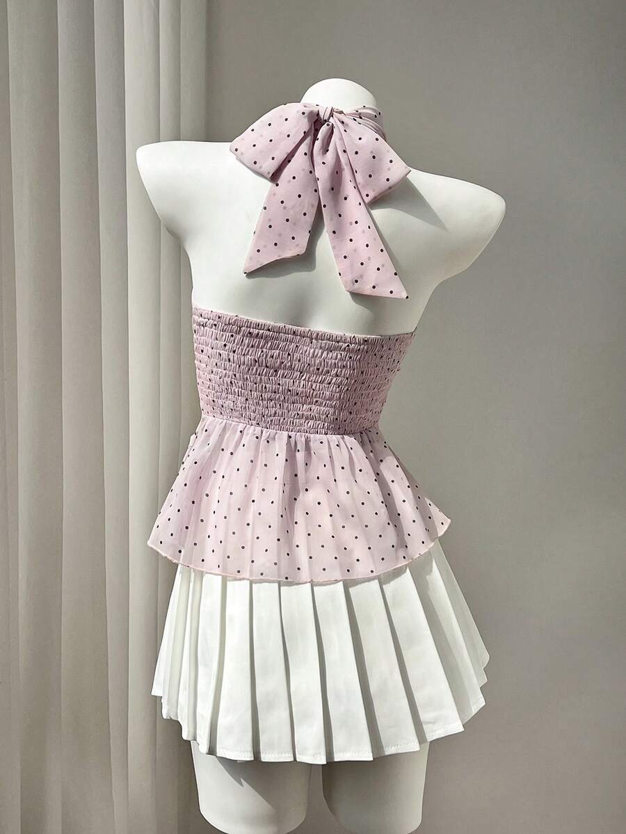 Women's white sleeveless halter neck top featuring pleated fabric, backless tie strap design, and a flared layered ruffle hem.