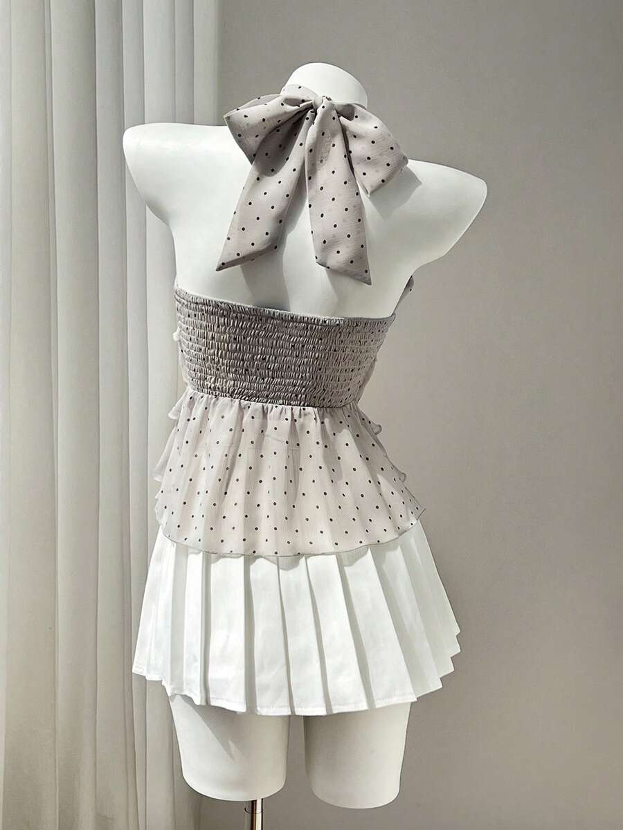Women's white sleeveless halter neck top featuring pleated fabric, backless tie strap design, and a flared layered ruffle hem.