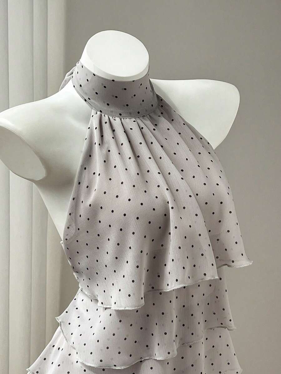Women's white sleeveless halter neck top featuring pleated fabric, backless tie strap design, and a flared layered ruffle hem.