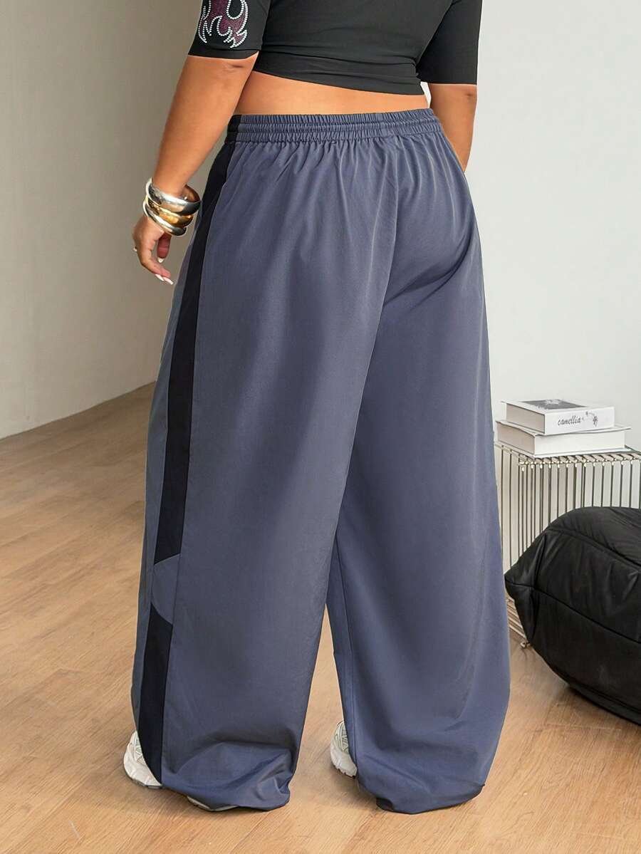 Women's plus size loose straight leg pants featuring a black and white color block design with side stripes and an elastic drawstring waist.