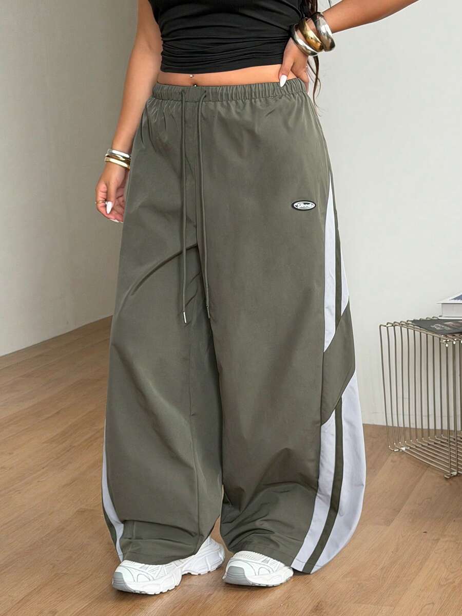 Women's plus size loose straight leg pants featuring a black and white color block design with side stripes and an elastic drawstring waist.