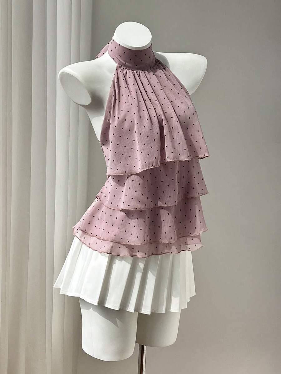 Women's white sleeveless halter neck top featuring pleated fabric, backless tie strap design, and a flared layered ruffle hem.