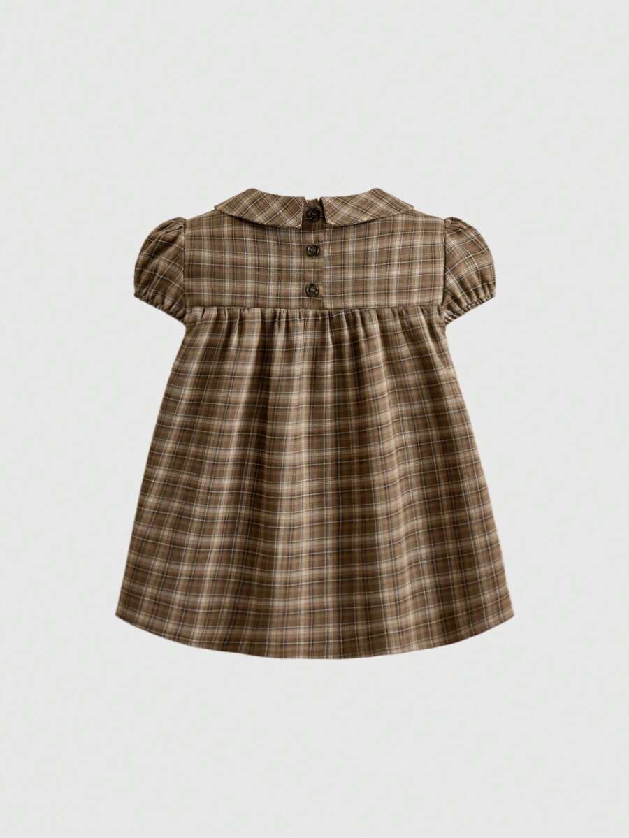 Short sleeve plaid shirt for women featuring a Peter Pan collar with a bow accent, puff sleeves, and a flared hem.