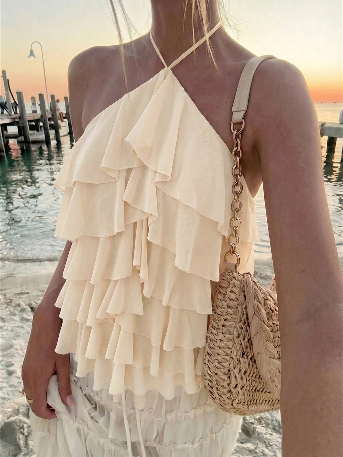 Women's sleeveless halter neck top featuring tiered ruffle layers, a backless cut, and an asymmetrical hem.