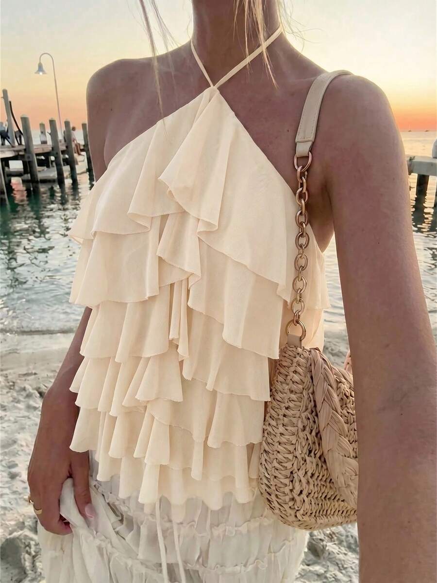 Women's sleeveless halter neck top featuring tiered ruffle layers, a backless cut, and an asymmetrical hem.