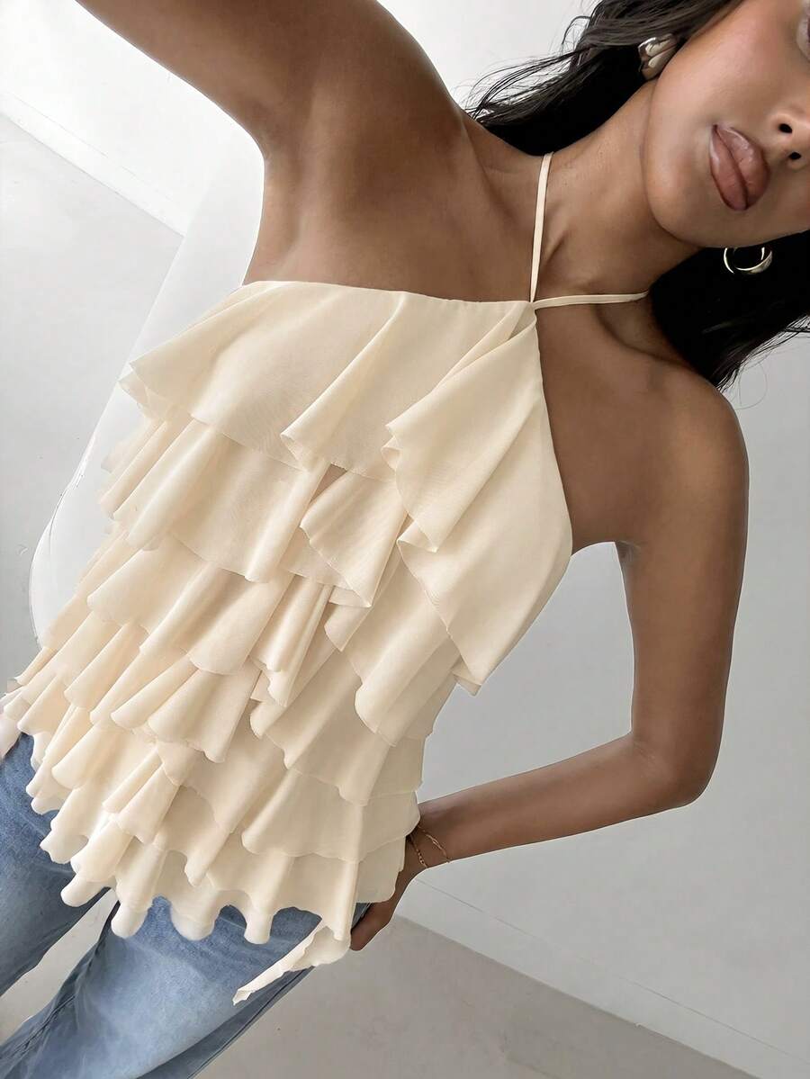 Women's sleeveless halter neck top featuring tiered ruffle layers, a backless cut, and an asymmetrical hem.