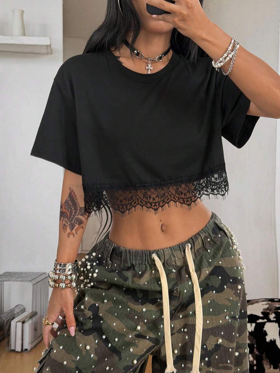 Women's short sleeve crop top with a round neckline and drop shoulder design in black knitted fabric.