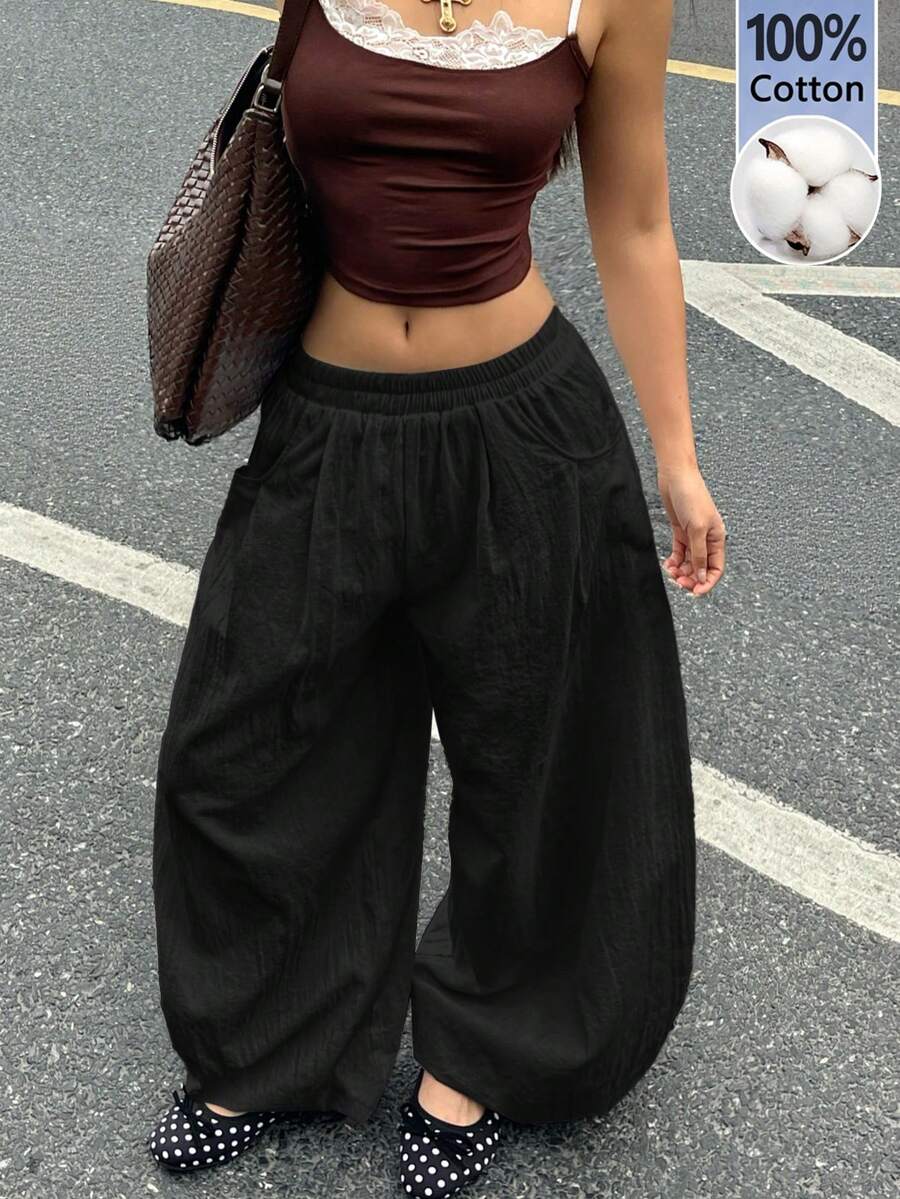 Women's loose-fit black bloomer pants made of 100% cotton featuring an elastic waistband and side pockets.