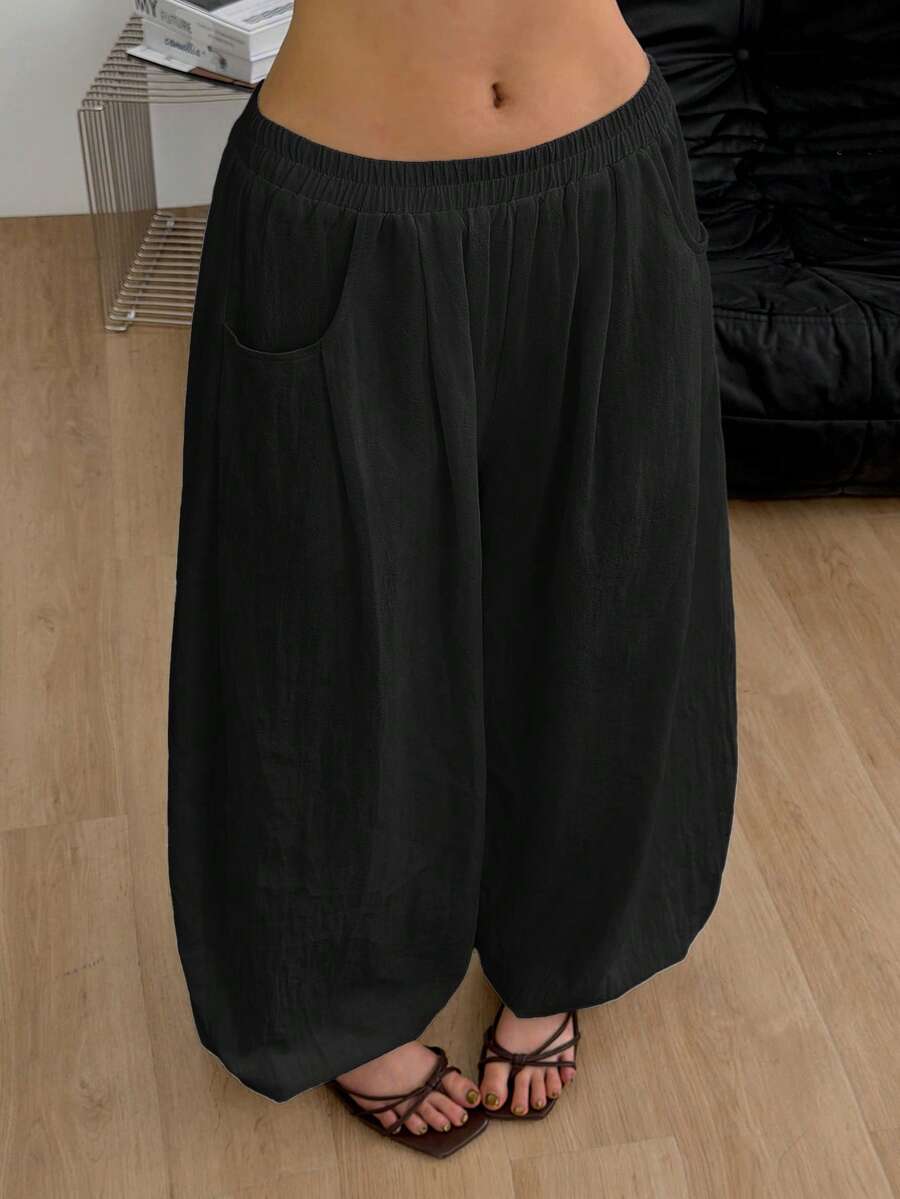 Women's loose-fit black bloomer pants made of 100% cotton featuring an elastic waistband and side pockets.