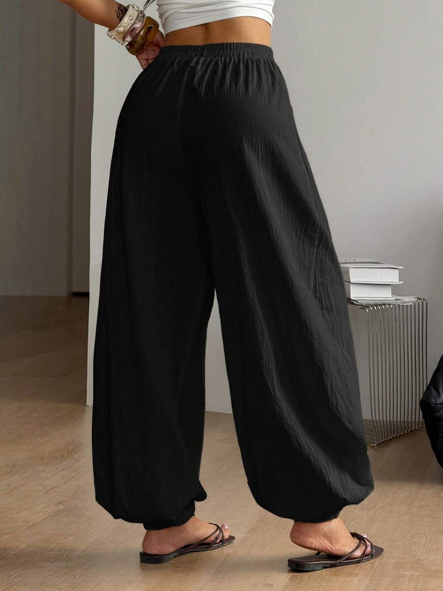Women's loose-fit black bloomer pants made of 100% cotton featuring an elastic waistband and side pockets.