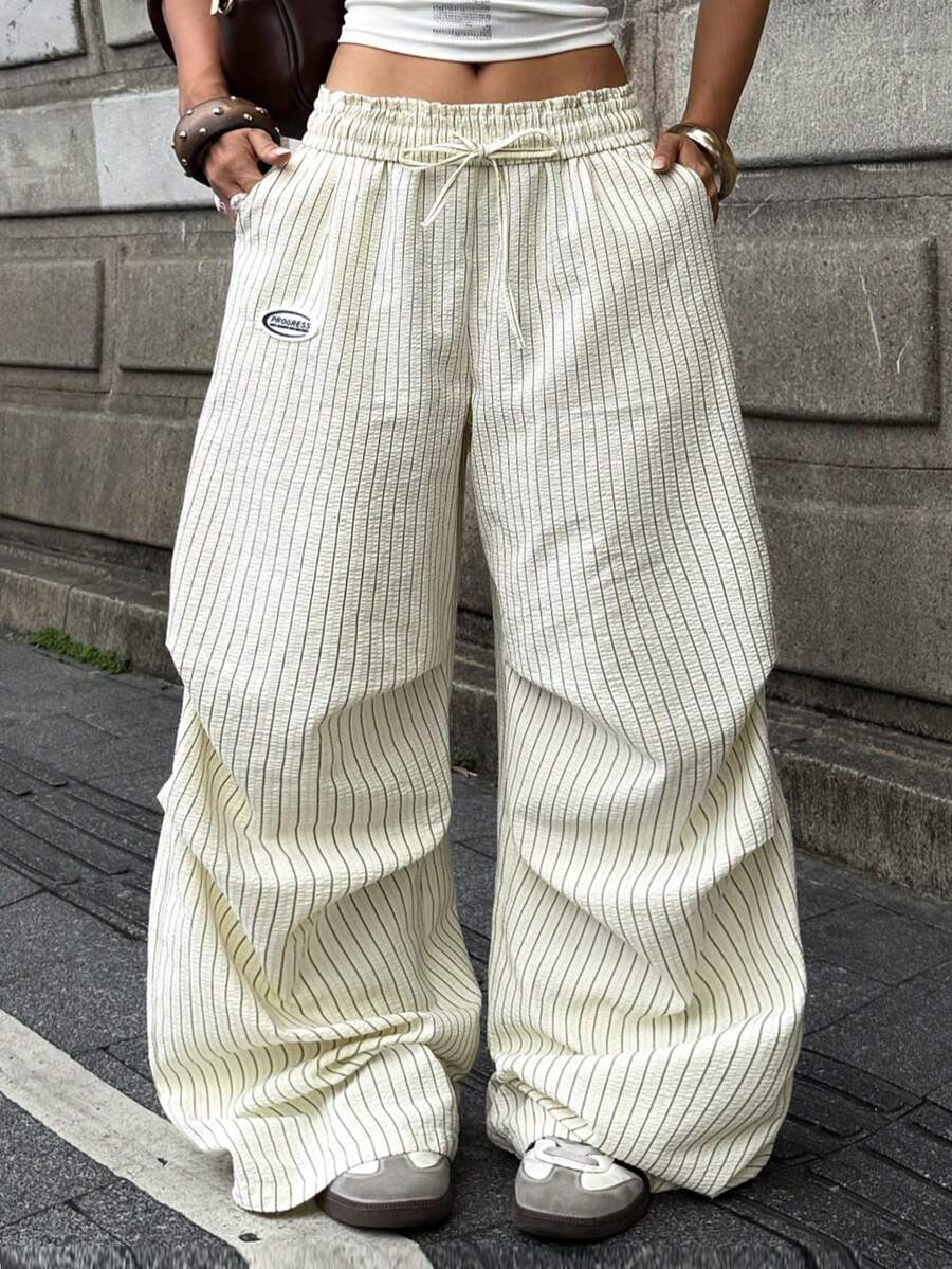 Women's black and white striped wide leg pants featuring an elastic drawstring waistband, side pockets, and a loose straight leg fit.