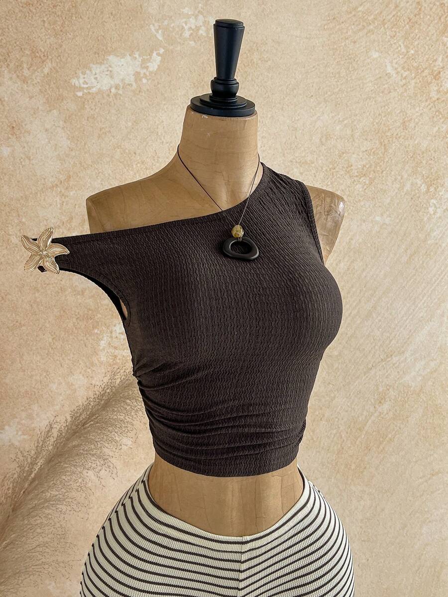 Women's black fuzzy knit two-piece set with an asymmetrical crop camisole top featuring ruched detail and cutout back, paired with matching mini shorts.