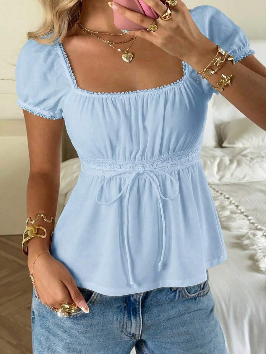 Women's black short puff sleeve top featuring a square neckline, ruched bust detail, and flared ruffle hem.
