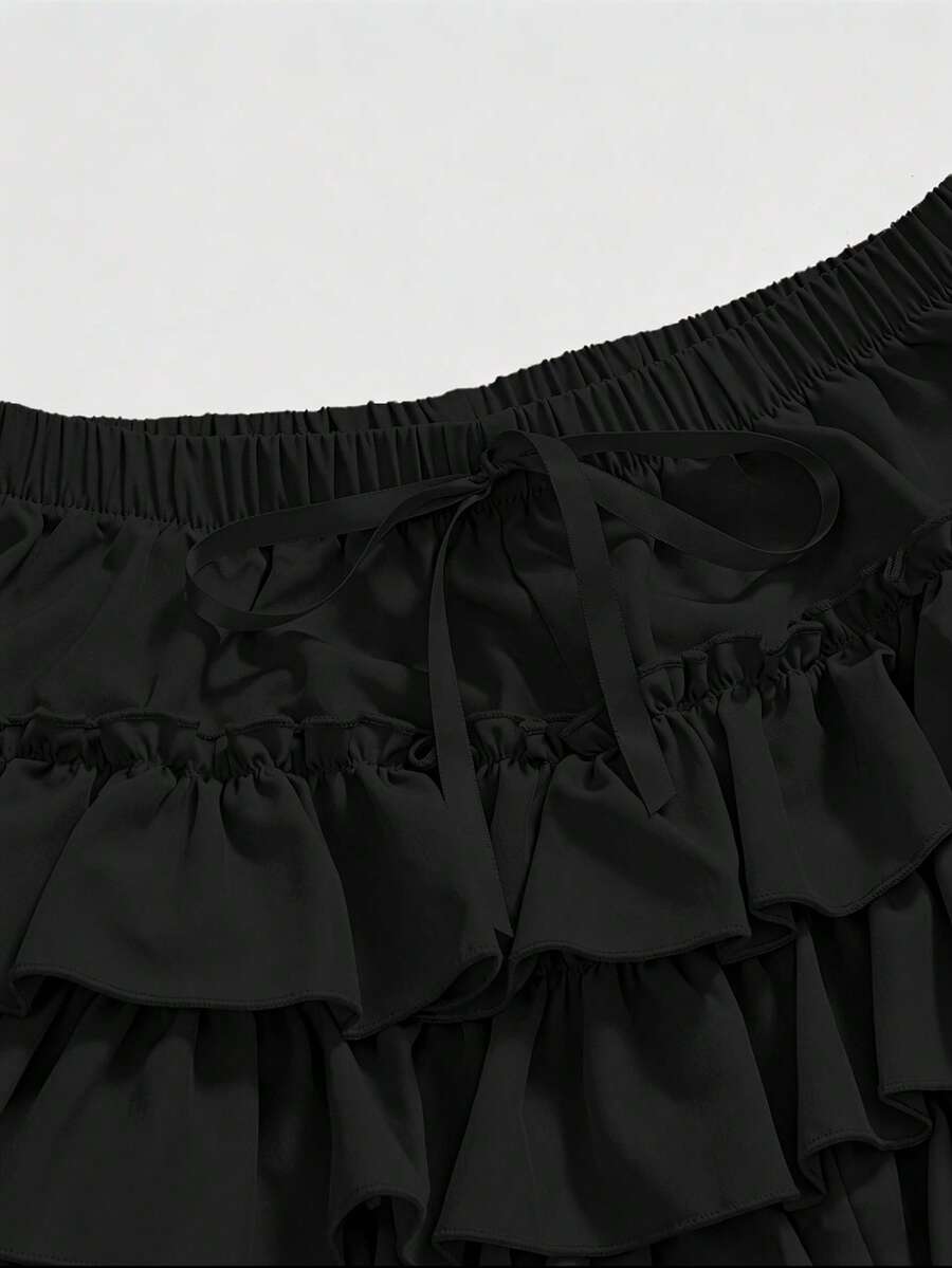 Women's tiered ruffle skort shorts featuring an elastic mid waist with front tie knot detail in woven fabric.