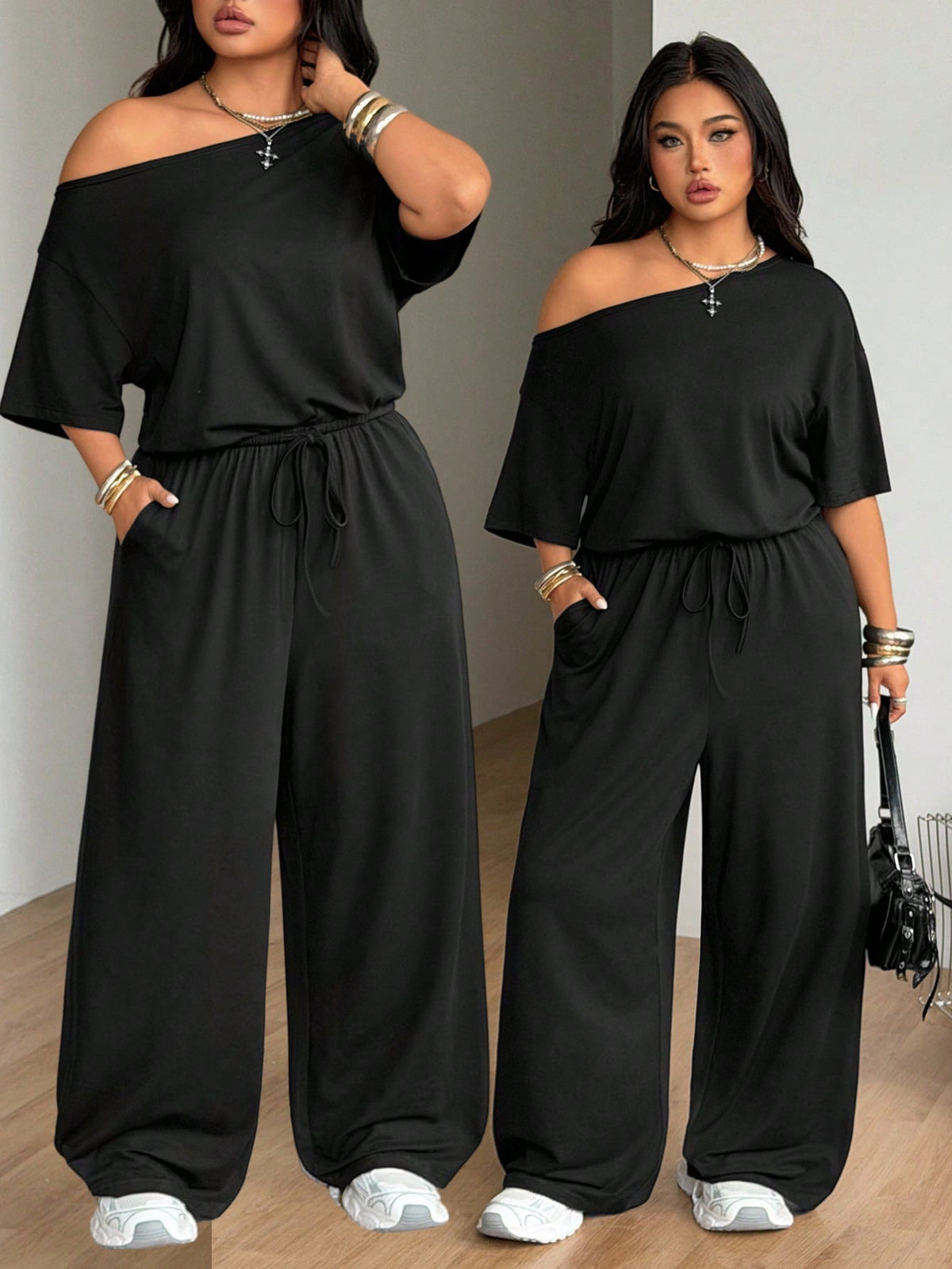 Plus size women's wide leg jumpsuit in dark grey featuring an asymmetrical neckline, short batwing sleeves, and a drawstring high waist with side pockets.