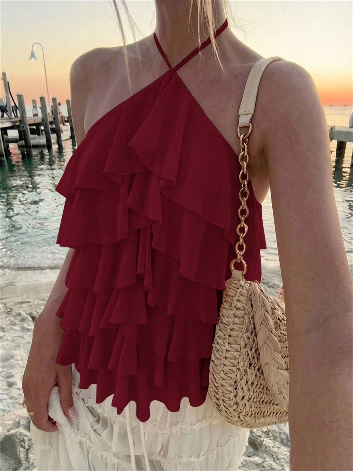 Women's sleeveless halter neck top featuring tiered ruffle layers, a backless cut, and an asymmetrical hem.