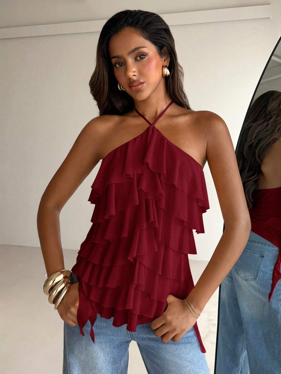 Women's sleeveless halter neck top featuring tiered ruffle layers, a backless cut, and an asymmetrical hem.