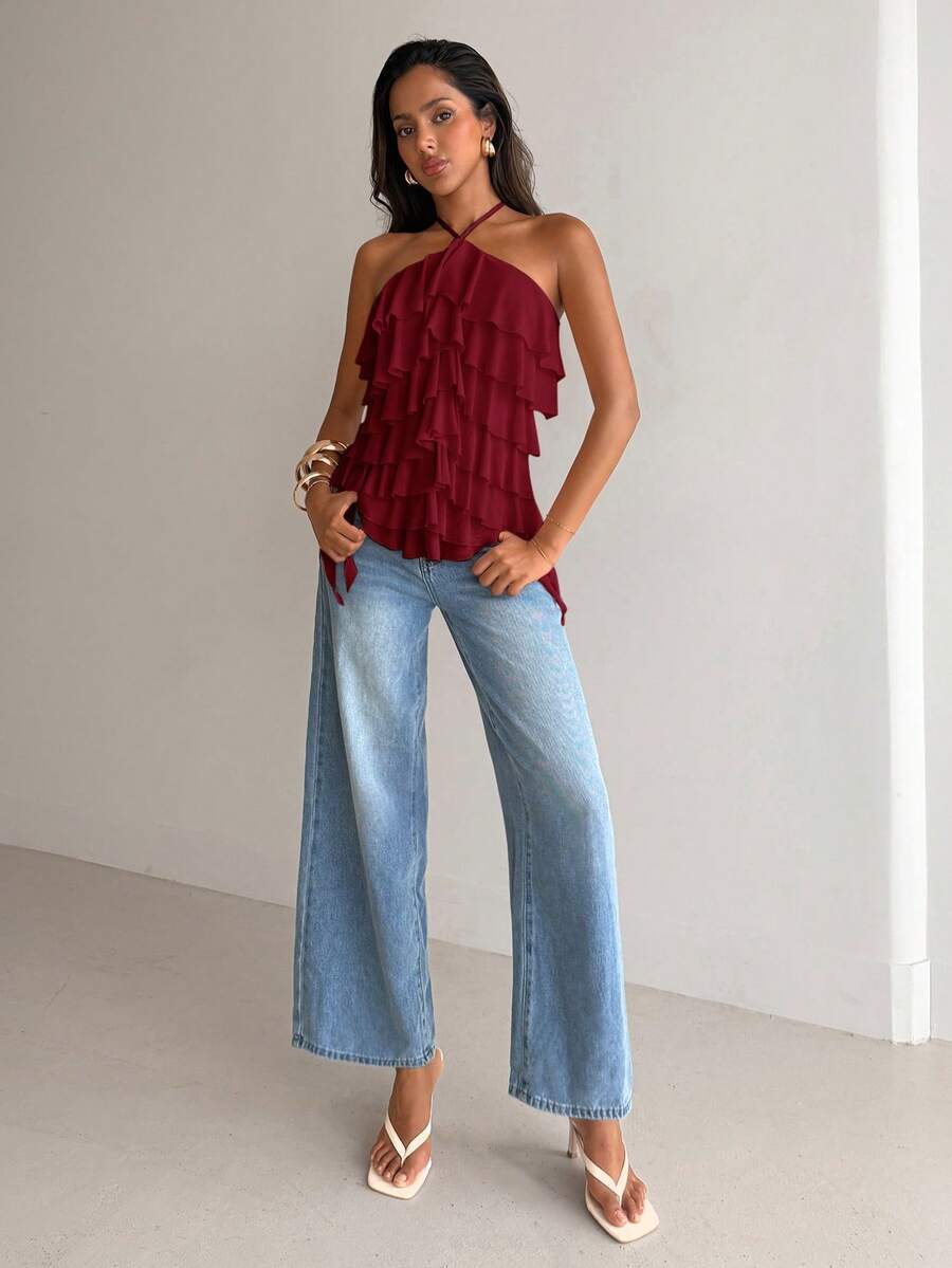 Women's sleeveless halter neck top featuring tiered ruffle layers, a backless cut, and an asymmetrical hem.