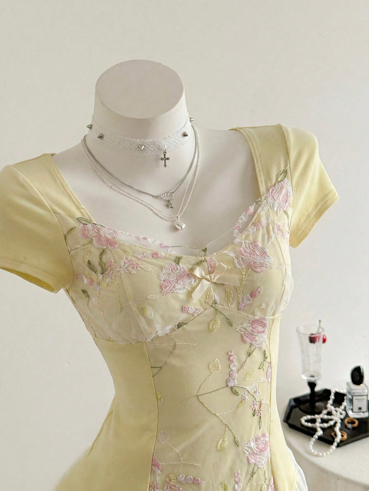 Women's pink short sleeve slim fit dress featuring a plant pattern, scoop neck, ruched appliques, and button front detail.