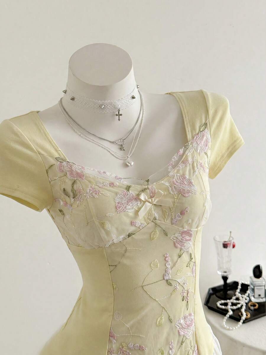 Women's pink short sleeve slim fit dress featuring a plant pattern, scoop neck, ruched appliques, and button front detail.