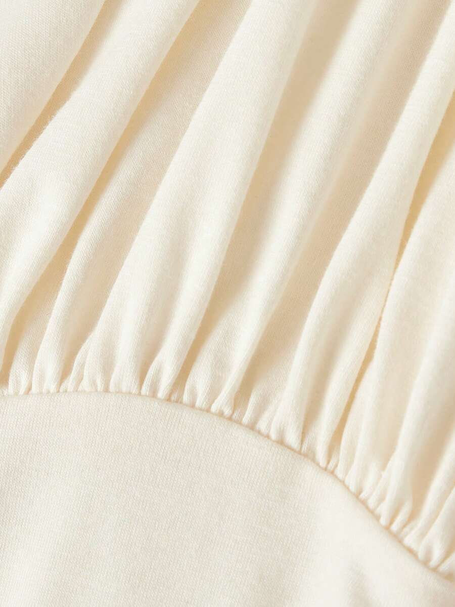 Women's sleeveless high-neck halter crop top in apricot with ruched knot front detailing.
