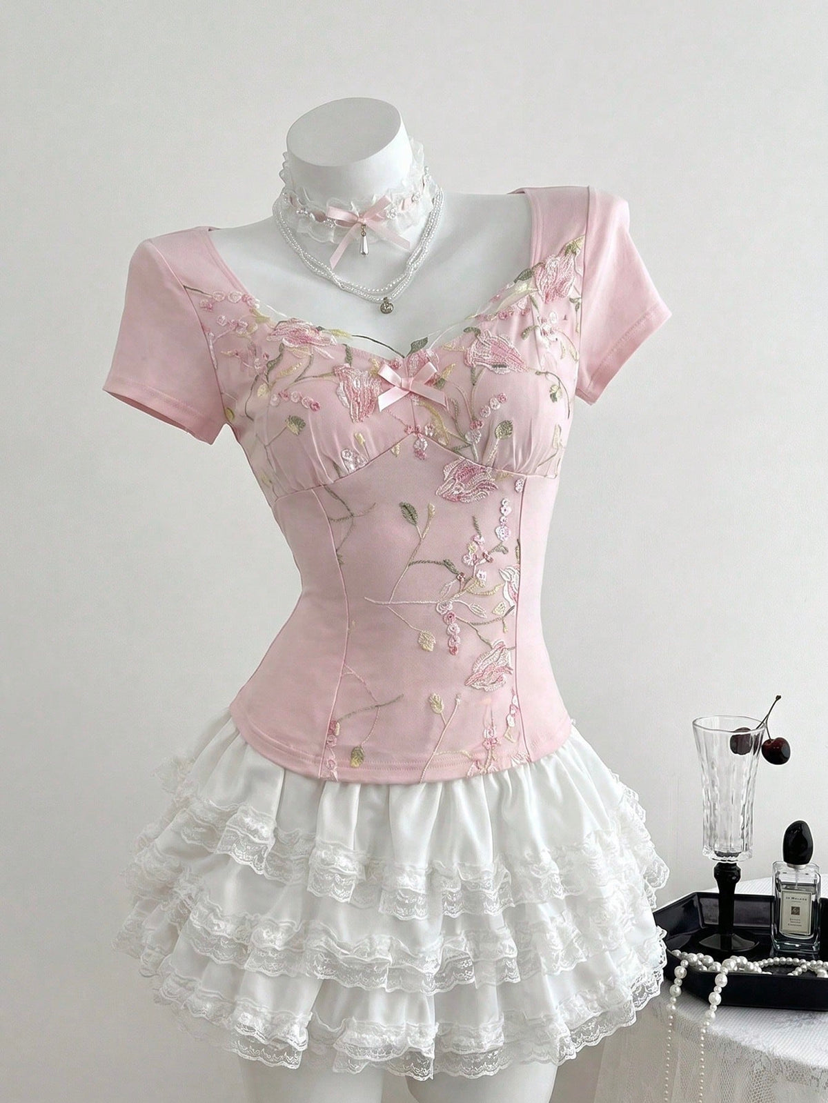Women's pink short sleeve slim fit dress featuring a plant pattern, scoop neck, ruched appliques, and button front detail.