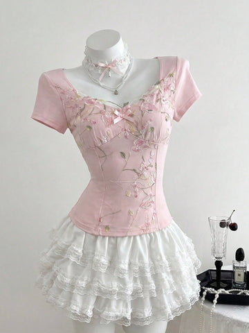 Women's pink short sleeve slim fit dress featuring a plant pattern, scoop neck, ruched appliques, and button front detail.