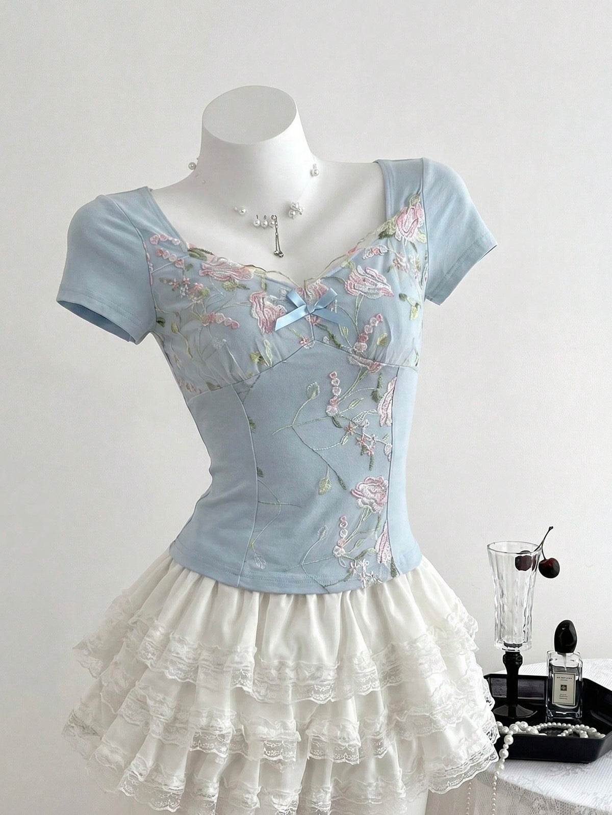 Women's pink short sleeve slim fit dress featuring a plant pattern, scoop neck, ruched appliques, and button front detail.