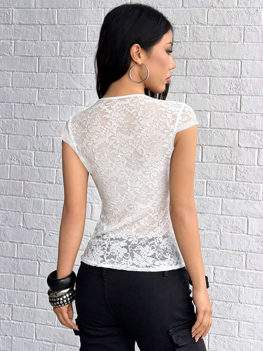 Women's black slim fit semi-sheer blouse featuring contrast lace detailing, a deep V hollow design with ring accent, asymmetrical hem, and cap sleeves.