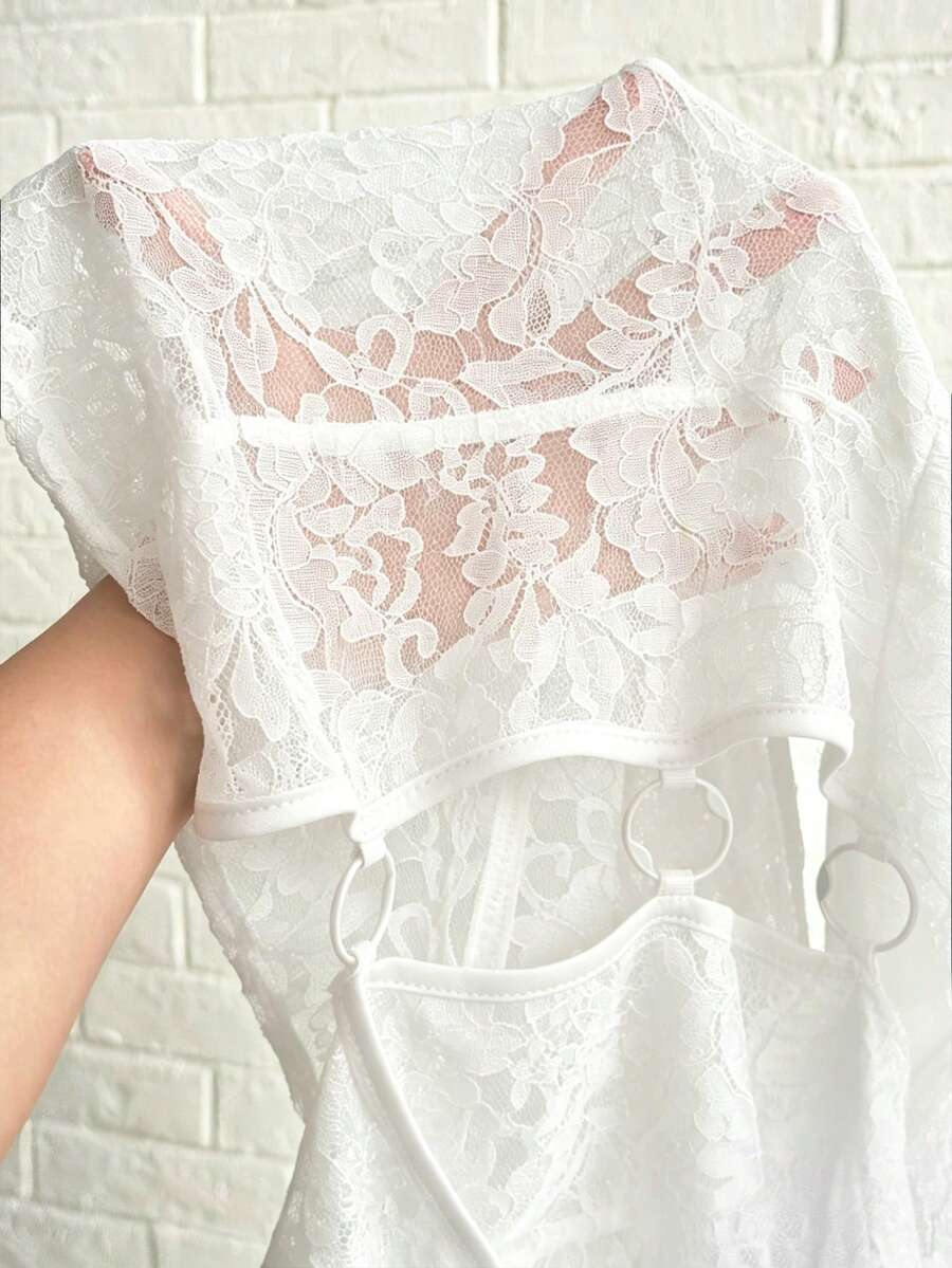 Women's black slim fit semi-sheer blouse featuring contrast lace detailing, a deep V hollow design with ring accent, asymmetrical hem, and cap sleeves.