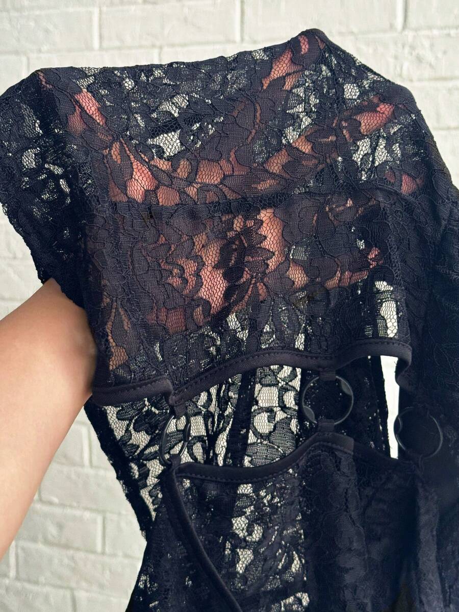 Women's black slim fit semi-sheer blouse featuring contrast lace detailing, a deep V hollow design with ring accent, asymmetrical hem, and cap sleeves.