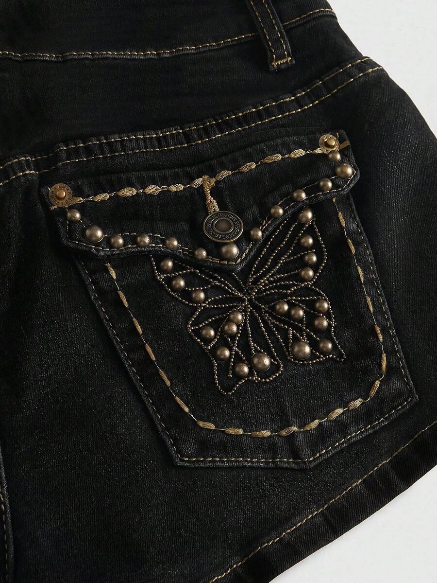 Women's Y2K low waist distressed shorts featuring butterfly studded details, pockets, and a zipper fly closure.