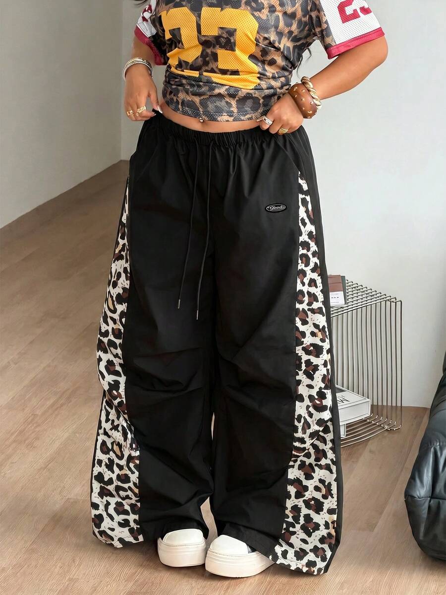 Women's high waist wide leg pants in black featuring leopard print patchwork details and an elastic drawstring waistband.