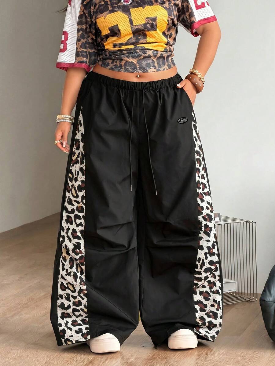 Women's high waist wide leg pants in black featuring leopard print patchwork details and an elastic drawstring waistband.