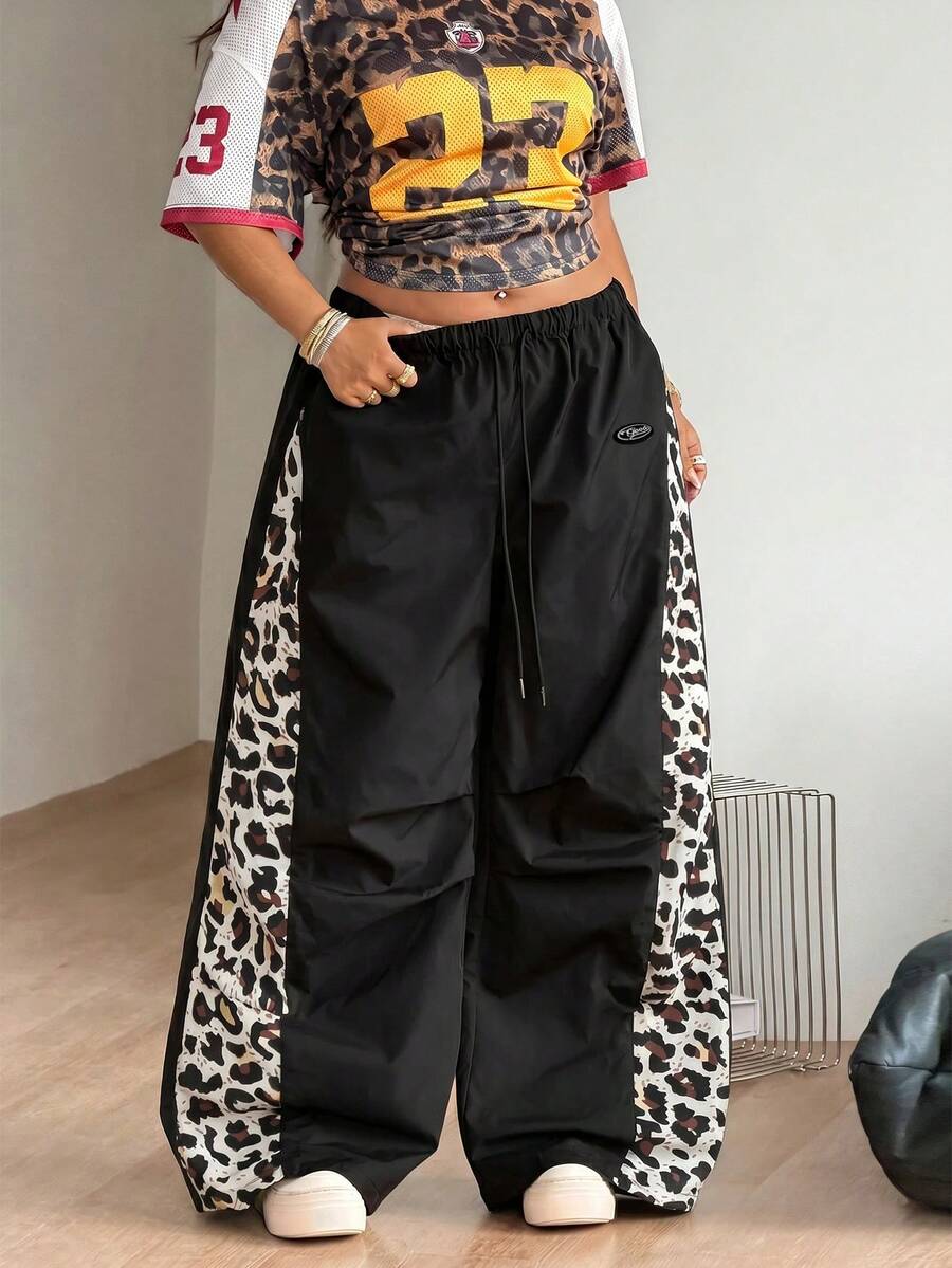 Women's high waist wide leg pants in black featuring leopard print patchwork details and an elastic drawstring waistband.