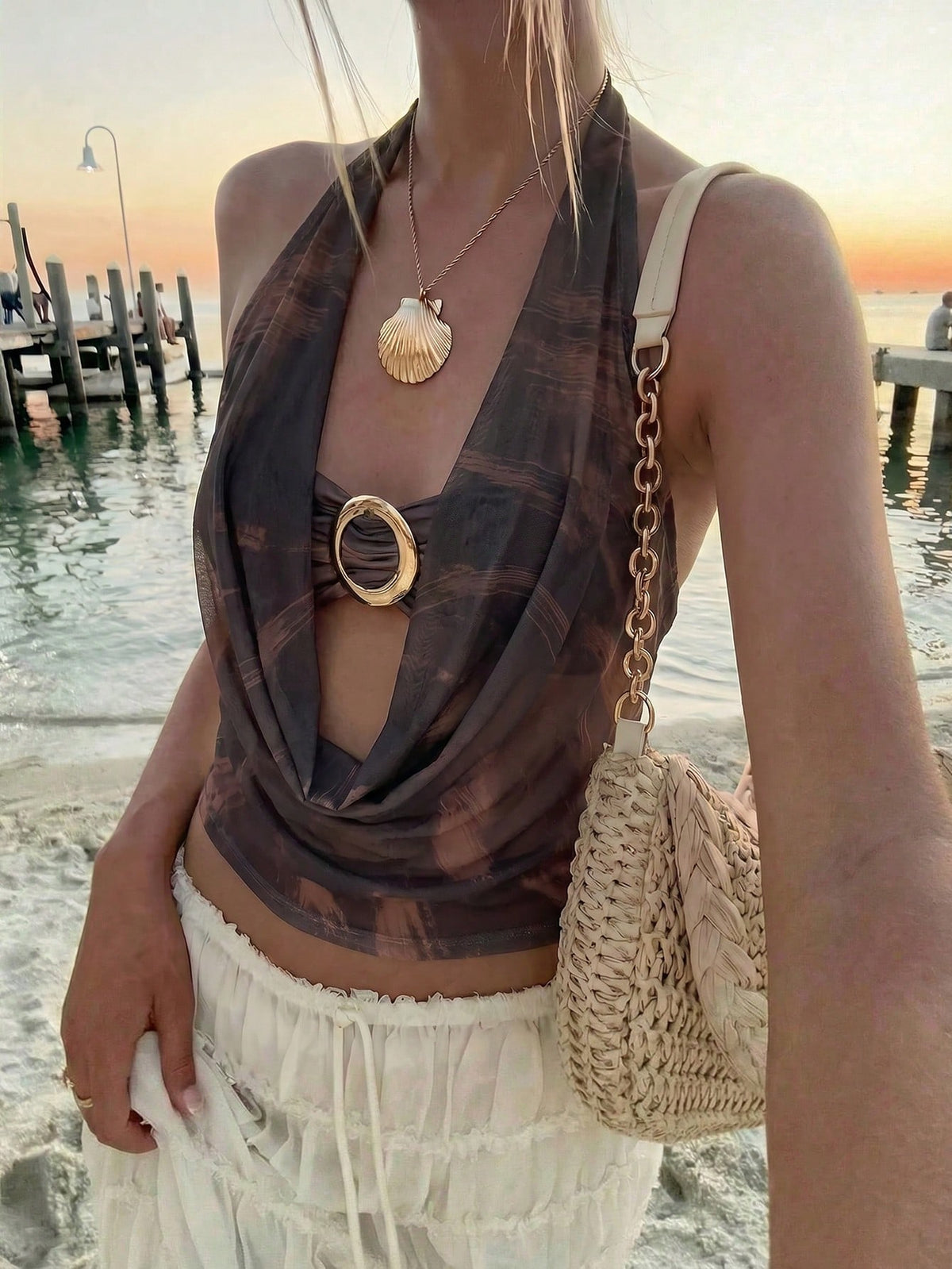 Brown and white polka dot semi-sheer halter camisole top with a plunging neckline, backless design, draped front, and metallic studded embellishments.