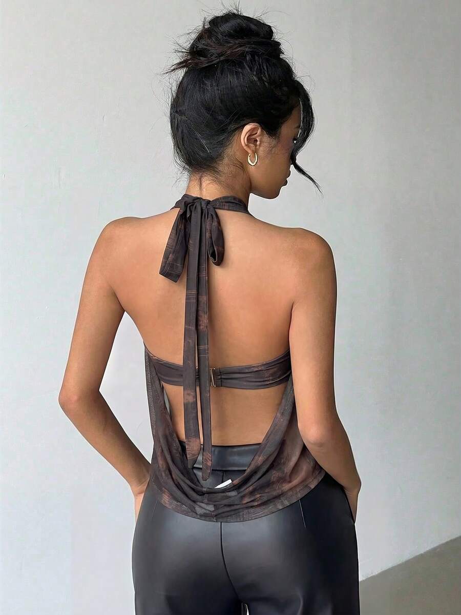 Brown and white polka dot semi-sheer halter camisole top with a plunging neckline, backless design, draped front, and metallic studded embellishments.