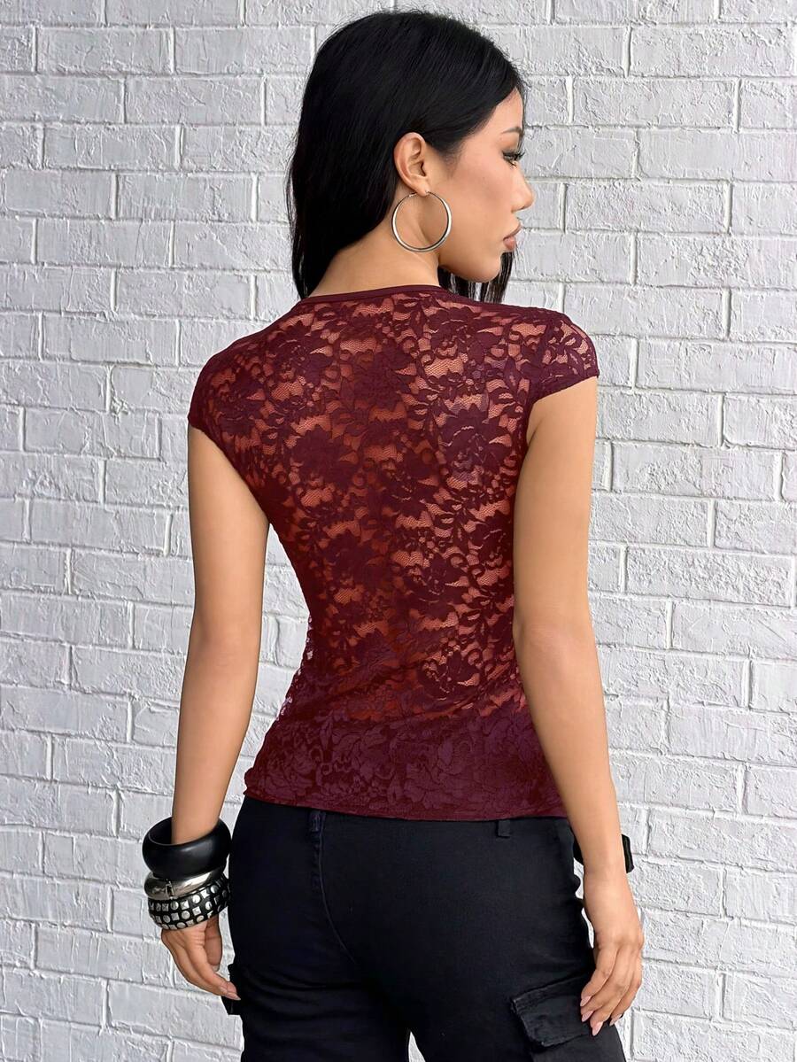 Women's black slim fit semi-sheer blouse featuring contrast lace detailing, a deep V hollow design with ring accent, asymmetrical hem, and cap sleeves.