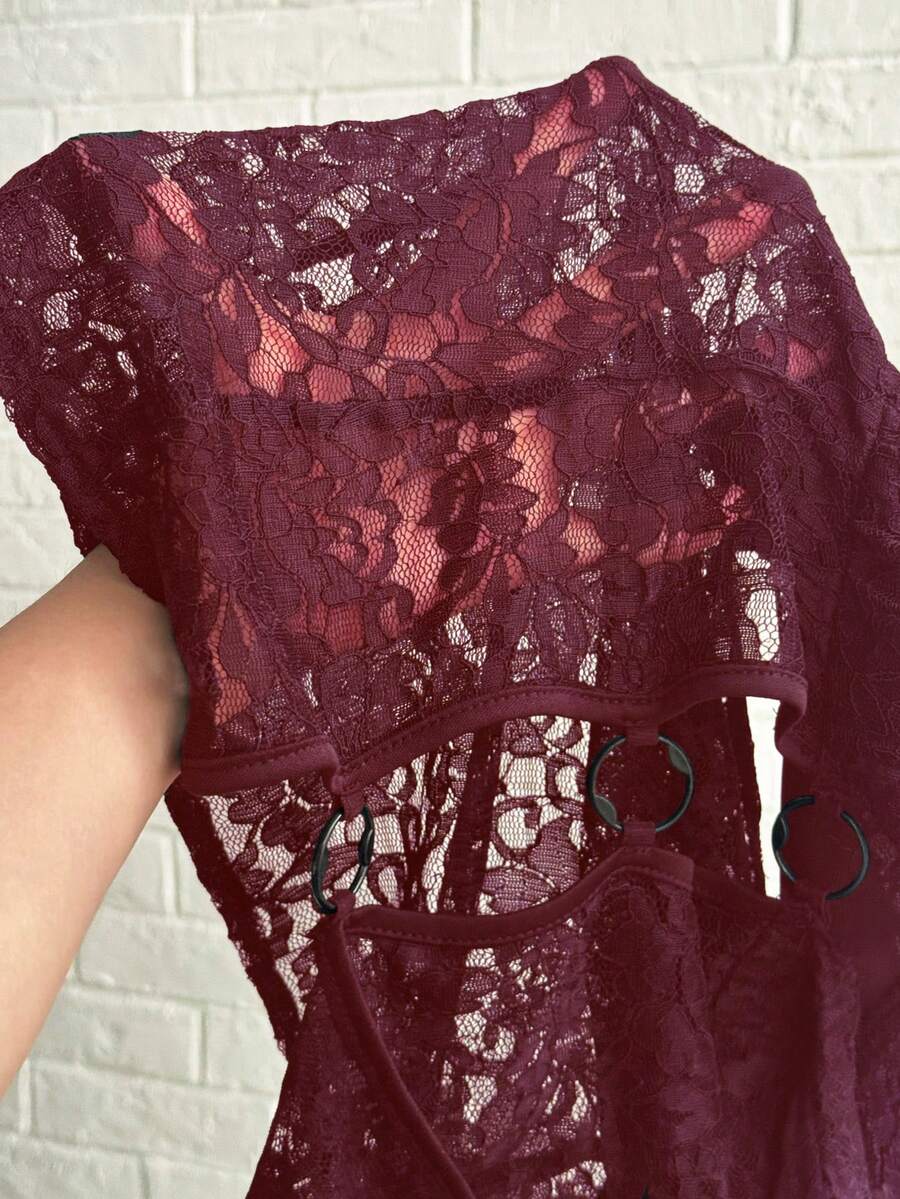Women's black slim fit semi-sheer blouse featuring contrast lace detailing, a deep V hollow design with ring accent, asymmetrical hem, and cap sleeves.